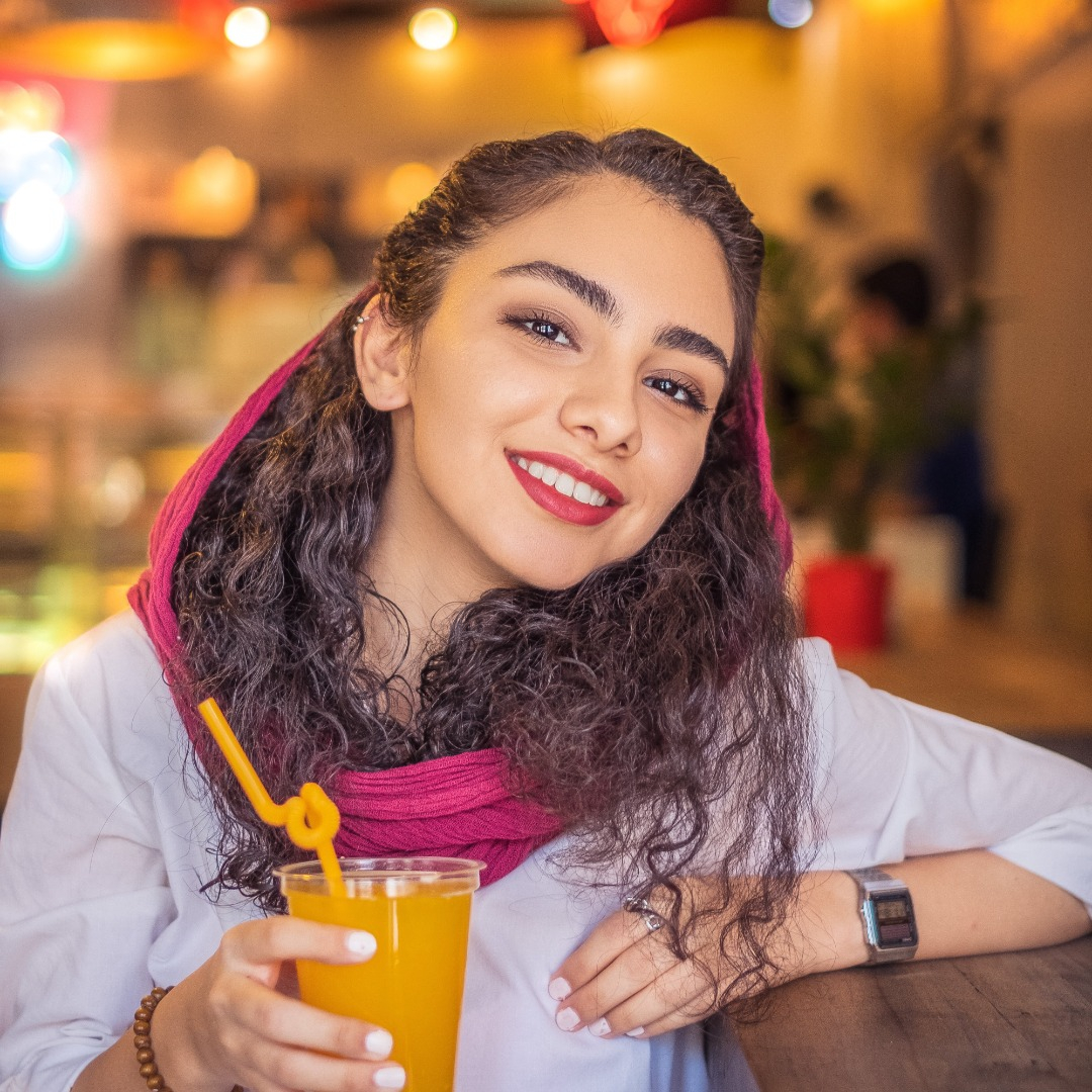 Young Iranian woman holding drink.